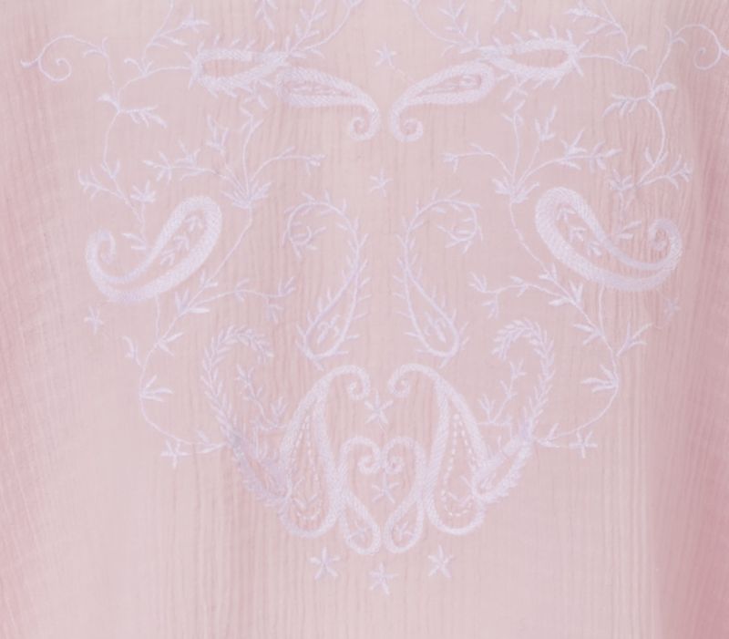 Stickerei der rosafarbenen Bluse im Detail, verspieltes Muster aus geschwungenen Linien.