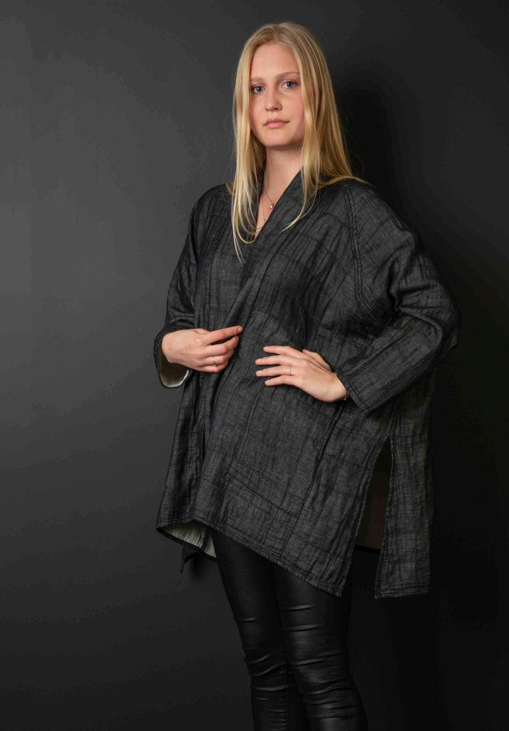 Young blonde woman wears black kimono jacket and black trousers