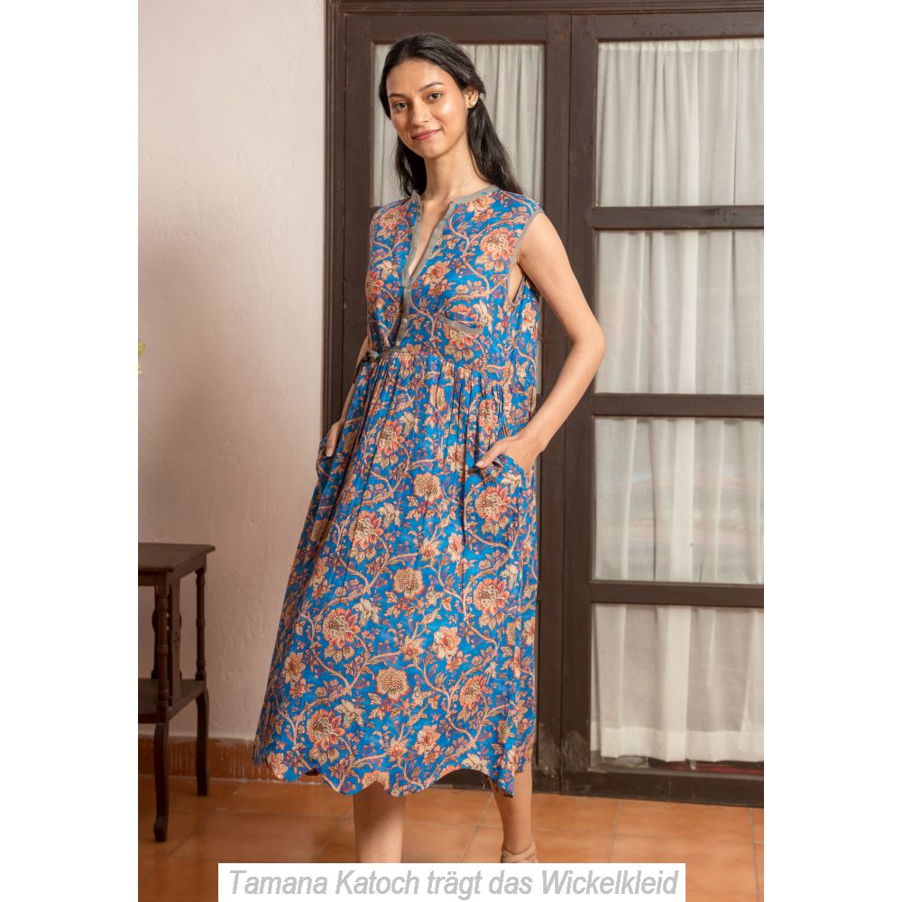 junge Frau trägt ein blaues  ärmelloses Wickelkleid mit braunem Blumenprint und Seitentaschen