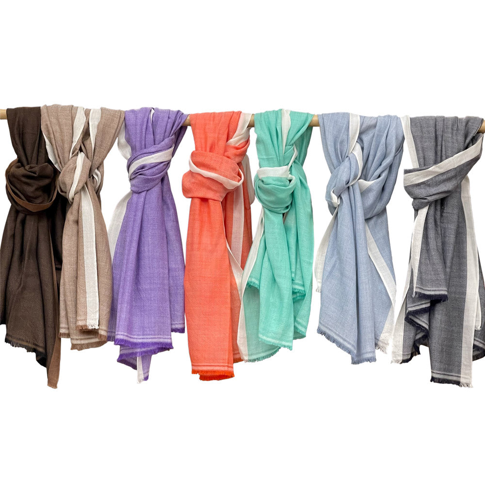 seven different coloured scarves hanging on a pole