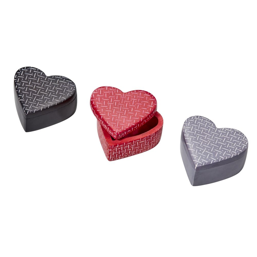 three small heart-shaped tins, left in black, closed, centre in red, half open, right in light grey, closed. The tins have a pattern