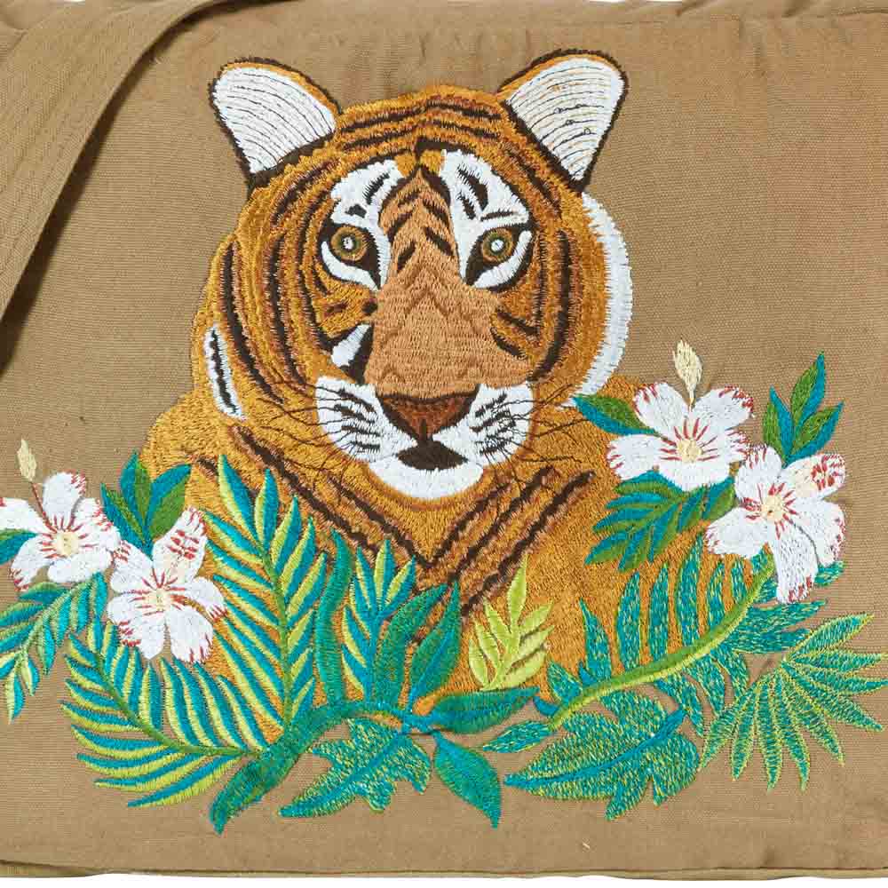 gestickter Tigerkopf hinter gestickten Blumen auf einem braunen Stoff