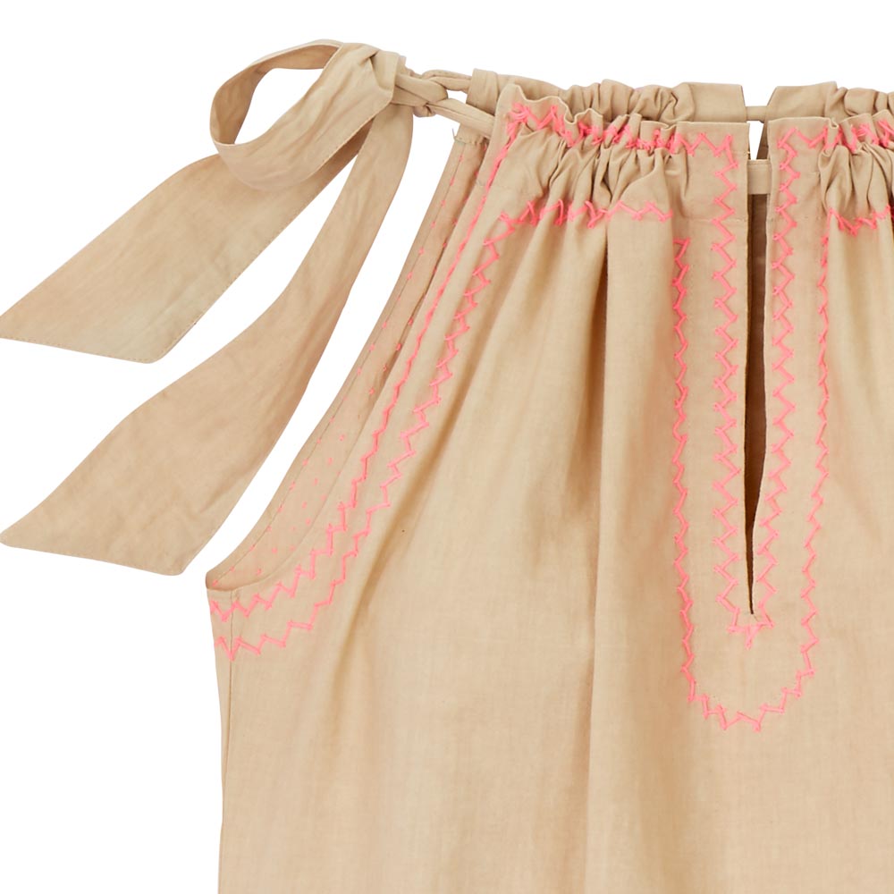 Detail, beige top. The drawstring neckline is closed with a bow. 
