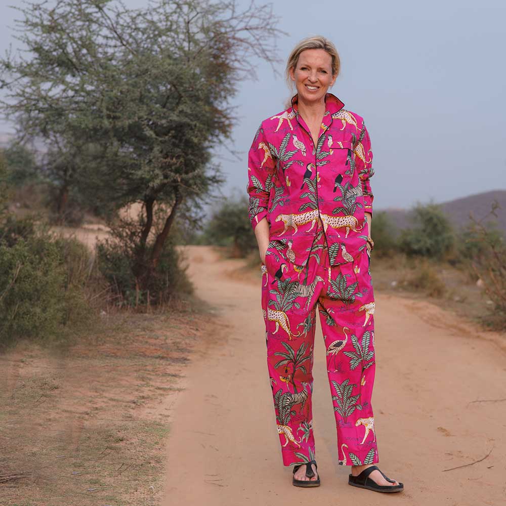 Frau in der afrikansichen Natur trägt einen pinkfarbenen Pyjma in Animal Print