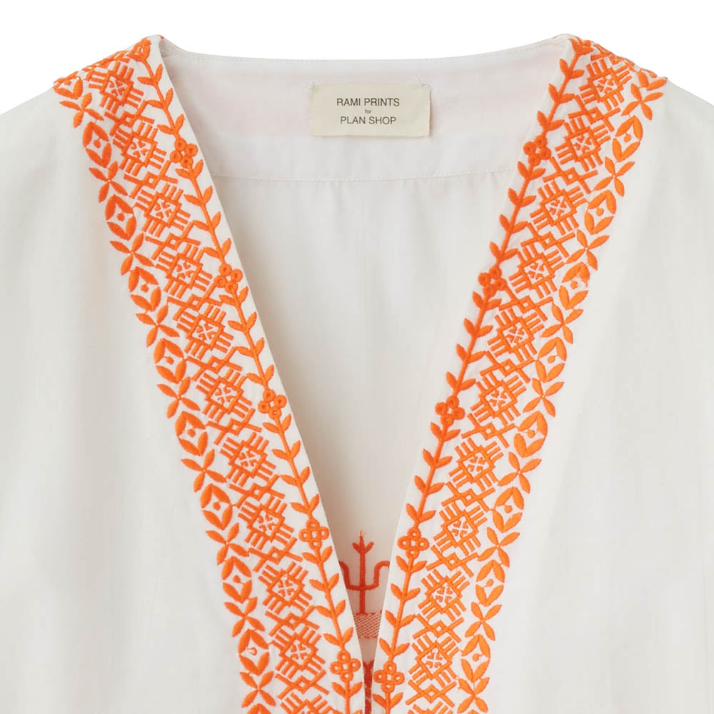 Teilanschicht einer orangefarbenen Stickerei auf weißer Bluse