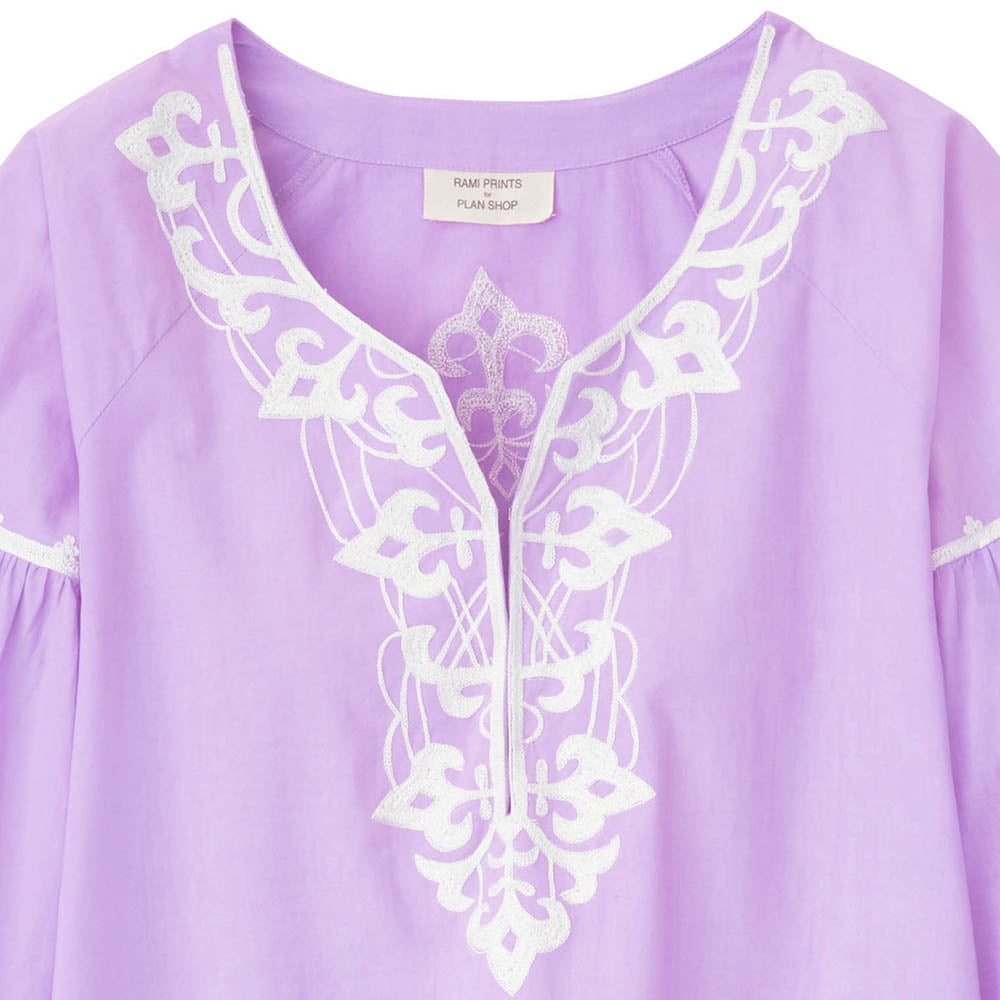 Close-up of a purple dress with white embroidery