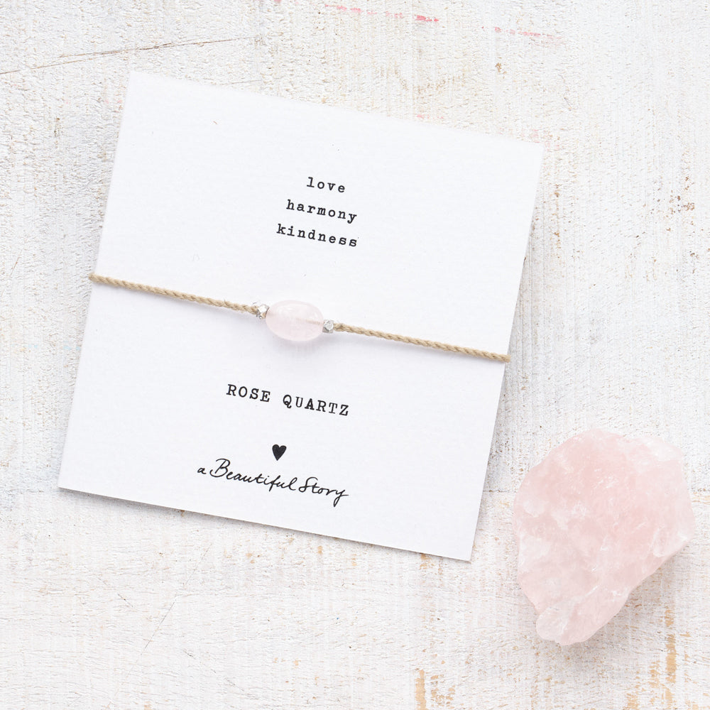 Greeting card with rose quartz ribbon, next to it a larger rose quartz stone, which illustrates the nature of the stone.