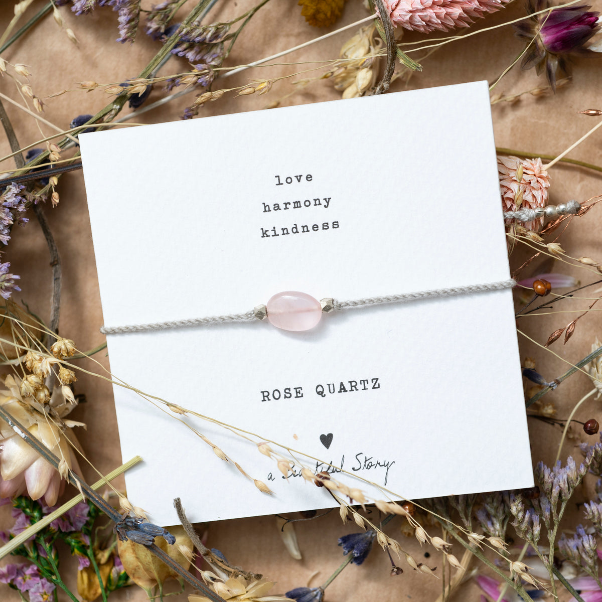 Mood picture: Greeting card with bracelet on a background consisting of dried flowers on wrapping paper.