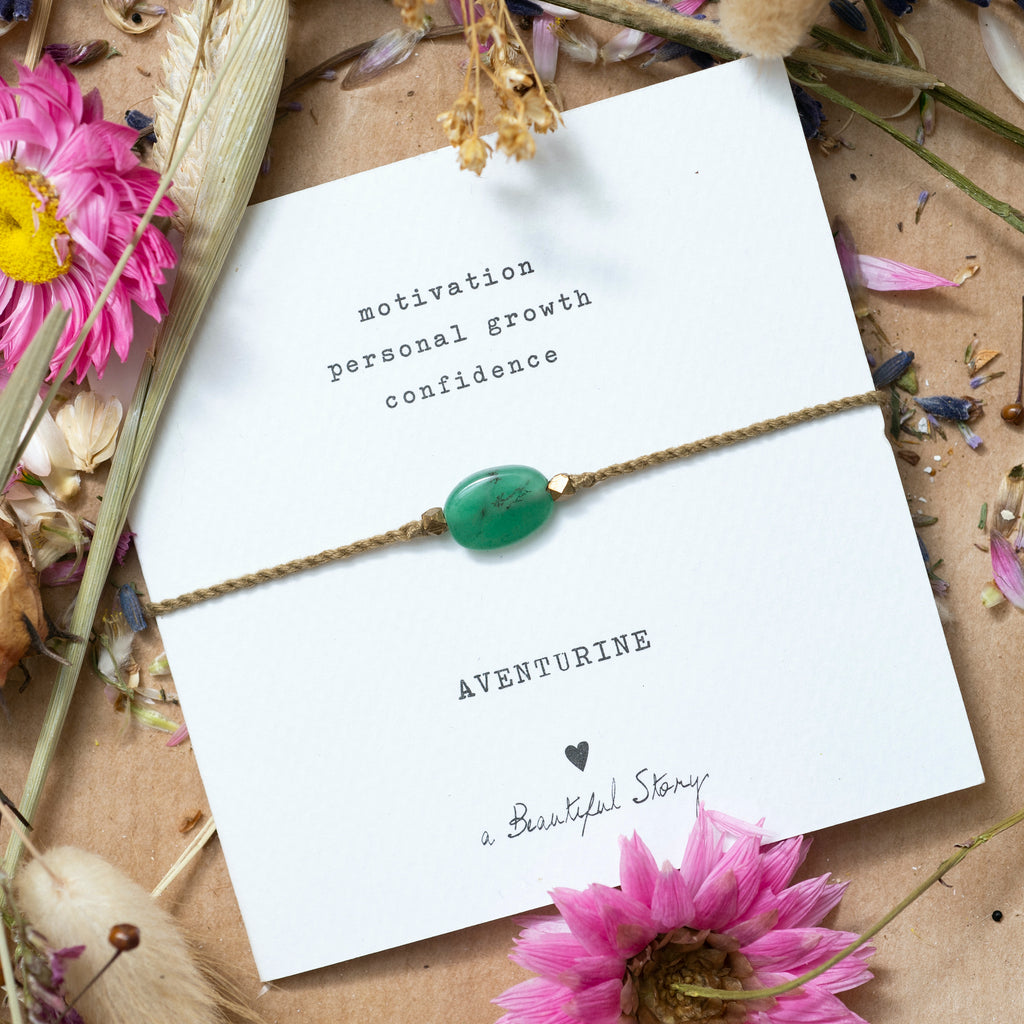 Mood picture of the Aventurine bracelet, the card with the bracelet lies on a background of wrapping paper with scattered dried flowers.