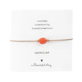 Zartes Armband aus goldfarbender Kordel mit Karneol Edelstein auf Grußkarte. Oben stehen die zugesprochenen Eingenschaften " Courage, Creativity, Transformation" Darunter steht "Carnelian", ein Herzchen und "A beautiful Story"