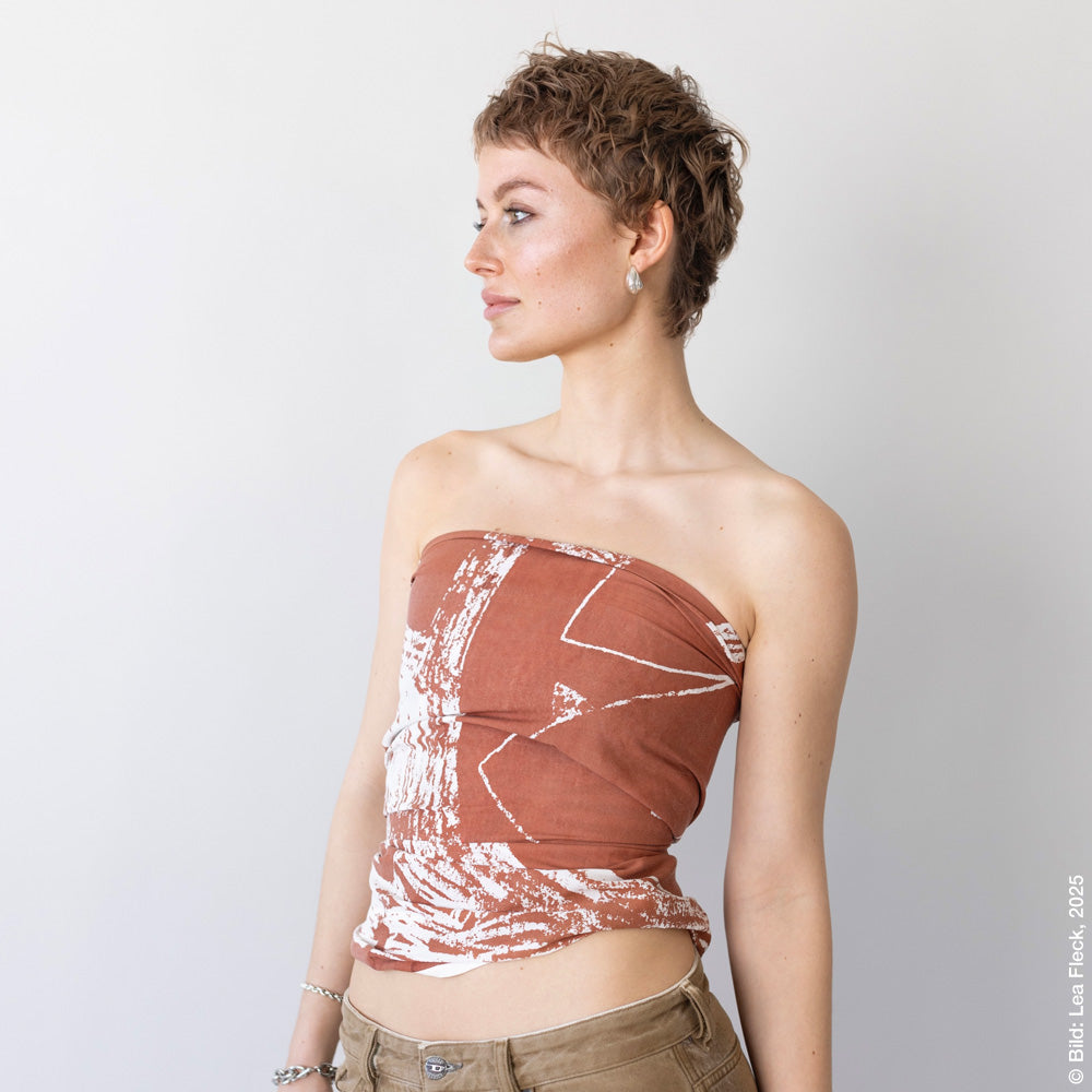 Woman wears a brown patterned off-the-shoulder top.