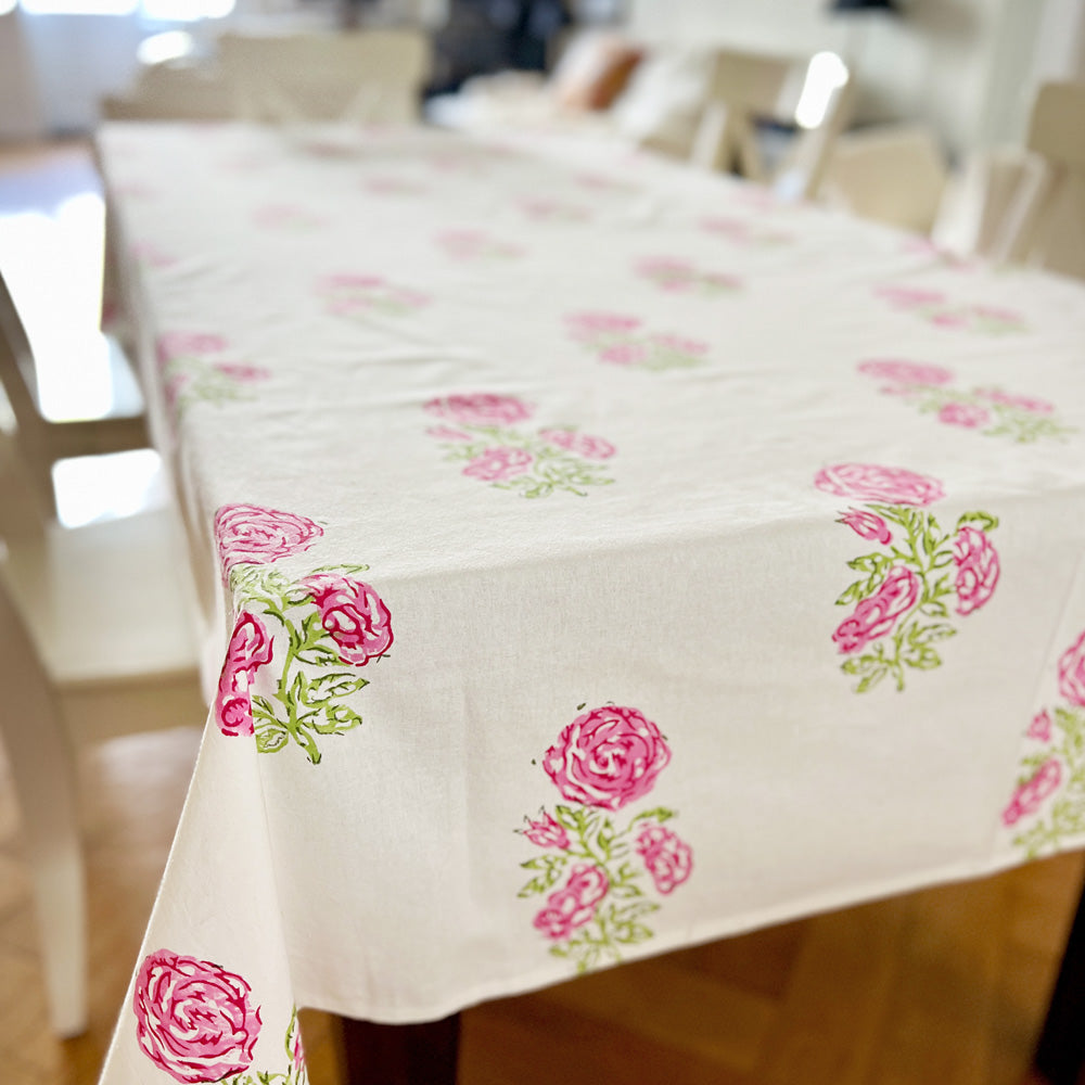 Tablecloth with rose print on a table with white chairs.