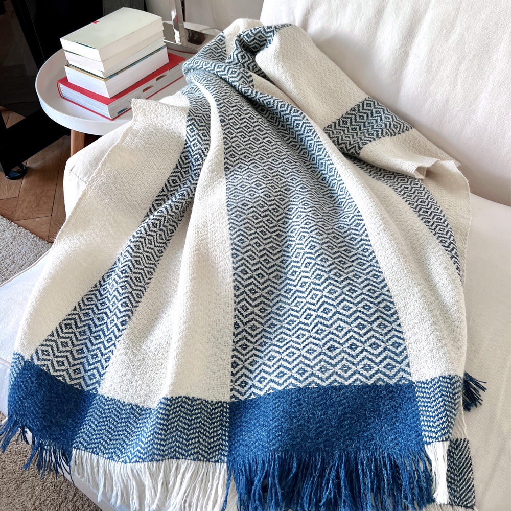 Wool white blue striped plaid on a natural coloured armchair in a cosy setting
