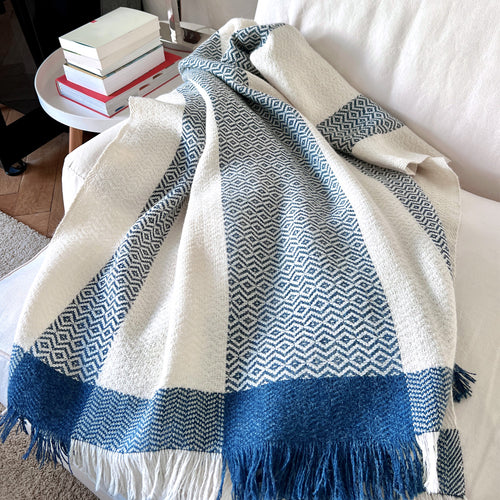 Wool white blue striped plaid on a natural coloured armchair in a cosy setting