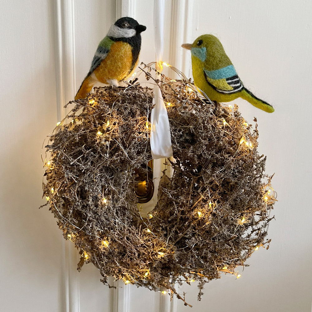 Hanging illuminated Christmas wreath with two decorative birds, a greenfinch and a great tit sitting on top