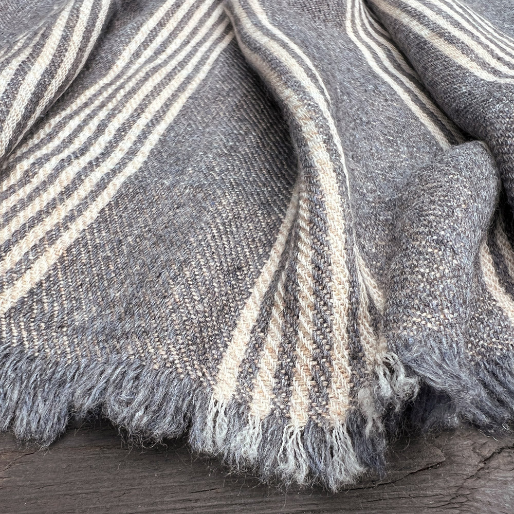 Partial cut-out of a scarf, grey beige striped with small fringes