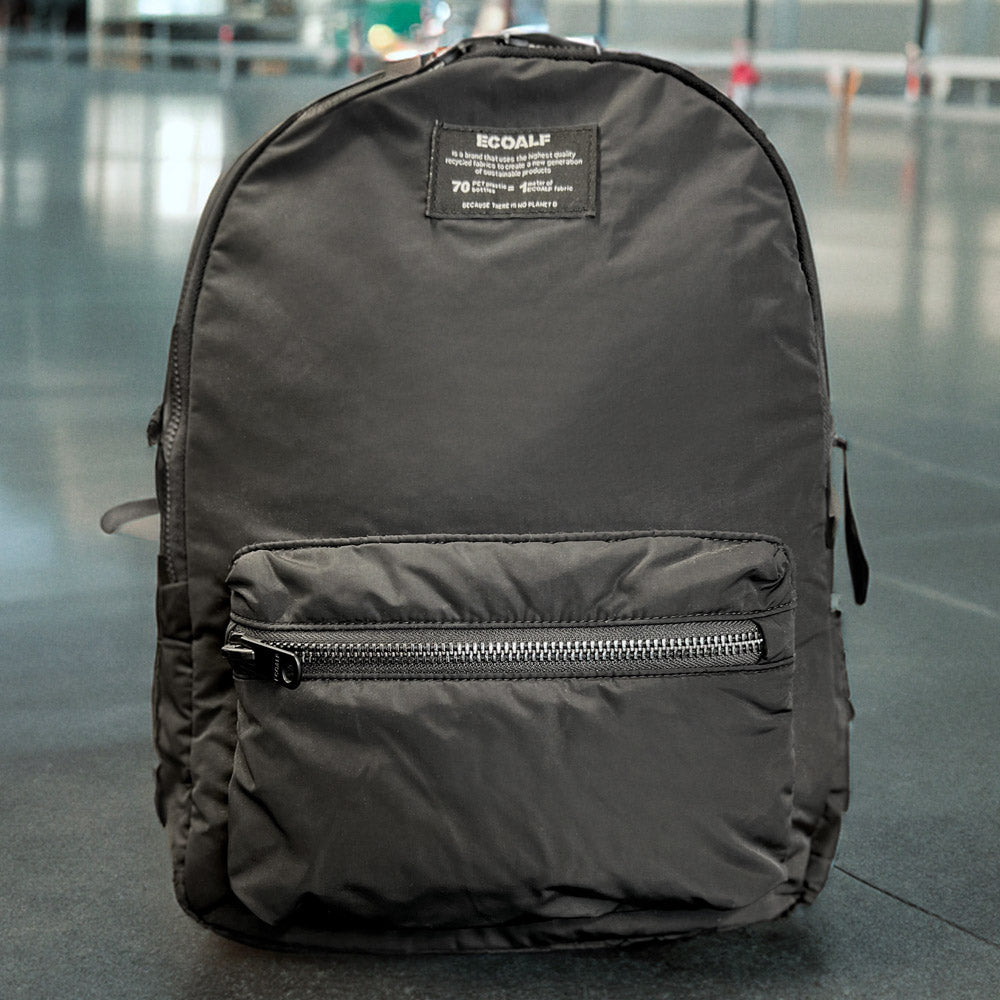 schwarzer Rucksack mit kleinem Hersteller-Label  und einem Extra Fach mit Reißverschluss
