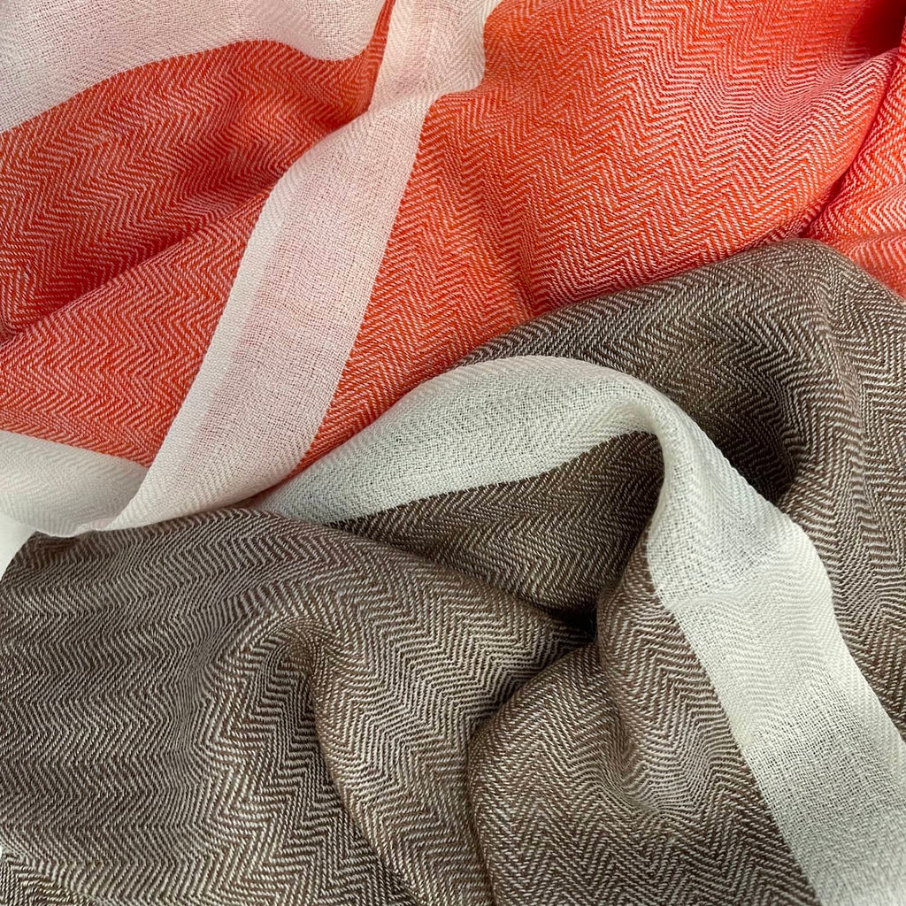 two scarves with herringbone pattern in the colours orange and brown, each with a white border