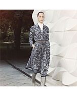 Junge Dame mit schwarz weiß gemusteter Bluse und gleichem Rock, sie trägt einen schmalen Gürtel und graue, knielange Stiefel dazu