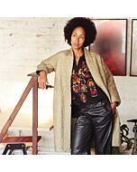 Dame mit schwarzer Hose, bestickter Bluse un einem offenen olivgrünen Steppmantel