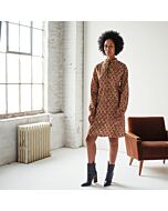 junge Frau trägt ein braunes knielanges Tunikakleid mit Muster, dazu hat sie schwarze Kurzstiefel an