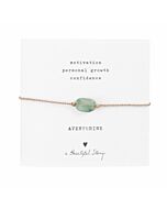 Armband aus goldfarbender Kordel mit grünem Edelstein Aventurin auf Karte, darüber steht "Motivation, personal growth" und "confidence". Darunter der Name des Steins: Aventurine, ein Herzchen und "A Beautiful Story"