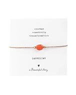 Zartes Armband aus goldfarbender Kordel mit Karneol Edelstein auf Grußkarte. Oben stehen die zugesprochenen Eingenschaften " Courage, Creativity, Transformation" Darunter steht "Carnelian", ein Herzchen und "A beautiful Story"