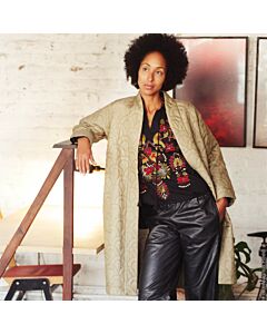 Dame mit schwarzer Hose, bestickter Bluse un einem offenen olivgrünen Steppmantel