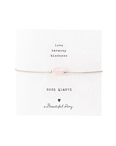 Zartes Armband: silberfarbenes Baumwollband mit einem Rosenquarz-Edelstein auf einer Grußkarte. Oben stehen die Worte "Love, Harmony, Kindness", unten ein Rosenquarz, ein Herz und "A Beautiful Story".
